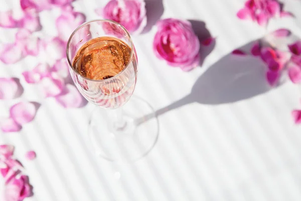 A glass of champagne and rose petals on a white background roman — Stock Photo, Image