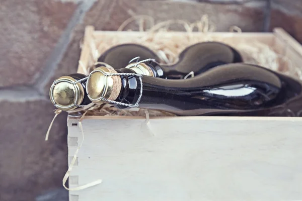 bir taş duvar arka plan üzerinde ahşap bir kutu içinde üç şampanya şişeleri