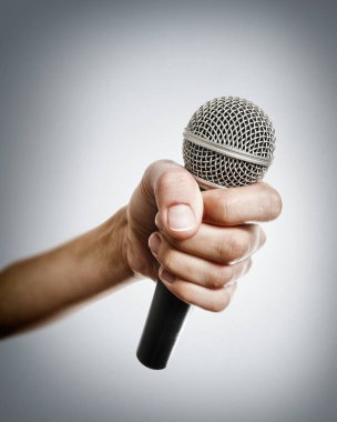 El ışık arka plan üzerinde mikrofon ile insan.