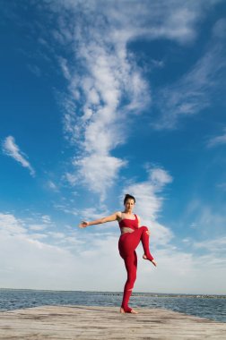 Genç kadın plajda yoga yapıyor.