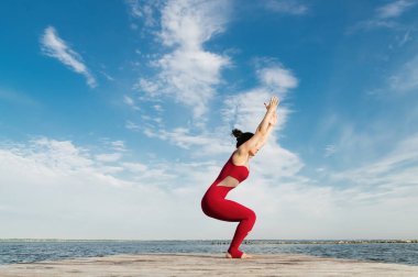 Genç kadın plajda yoga yapıyor.