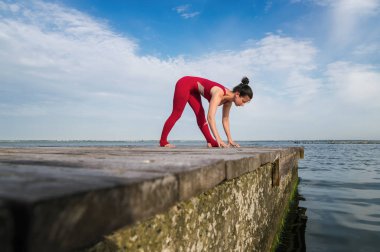 Genç kadın plajda yoga yapıyor.