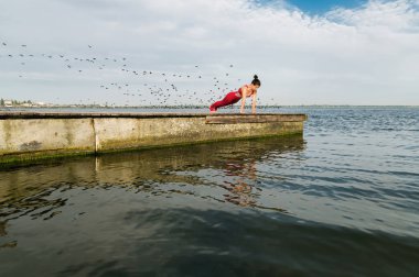 Genç kadın plajda yoga yapıyor.