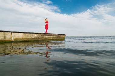 Genç kadın plajda yoga yapıyor.