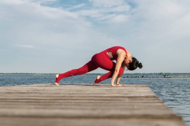 Genç kadın plajda yoga yapıyor.