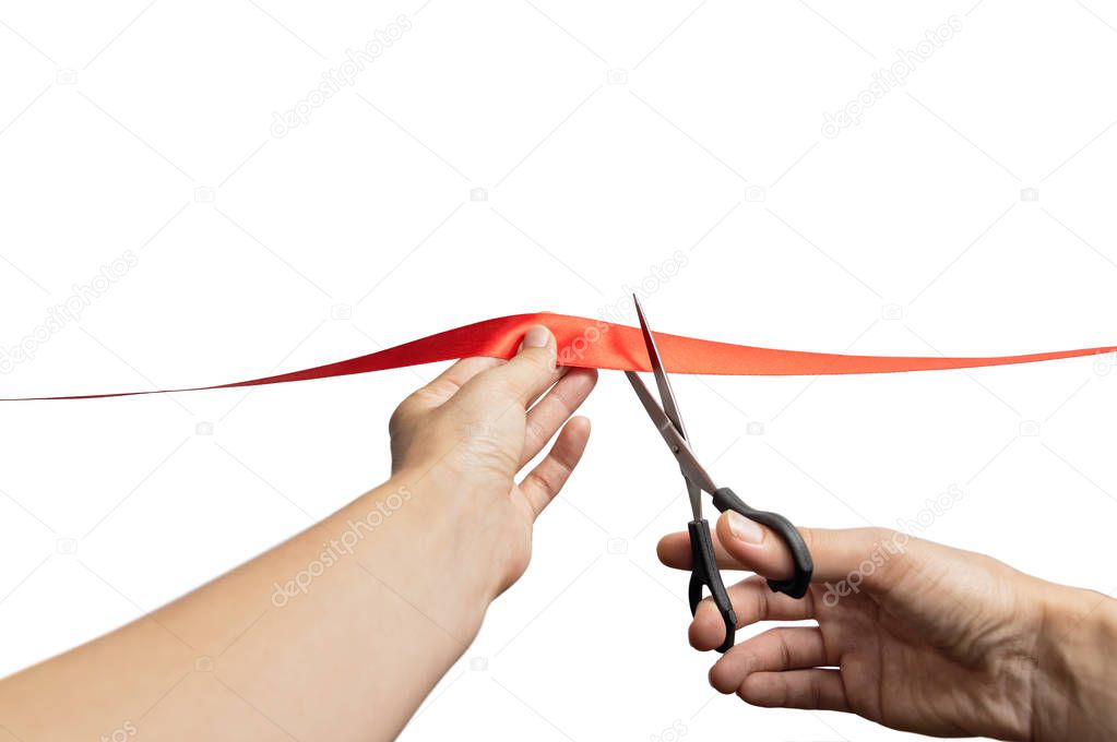 The concept of the grand opening of something. Scissors in female hands cuts the red satin ribbon.