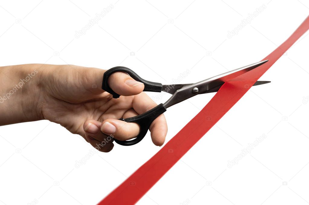 The concept of the grand opening of something. Scissors in female hands cuts the red satin ribbon.
