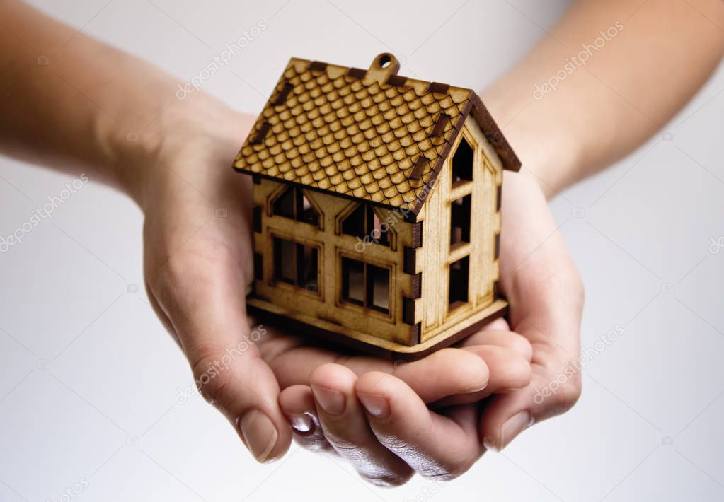 Hands with wooden model house. Concept of rent, purshase, insuranse, building real estate, eco house and other.