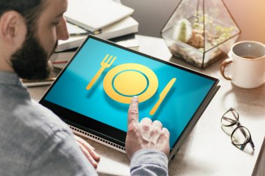 Masasında dizüstü bilgisayarı olan sakallı adam. Restoran simgesine basıyor. Internet üzerinden gıda sipariş kavramı. Görüntü