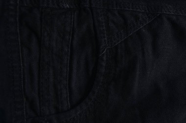 Görünür cep desenleri ve dikiş detaylarıyla yakın plan kot pantolon yığını..