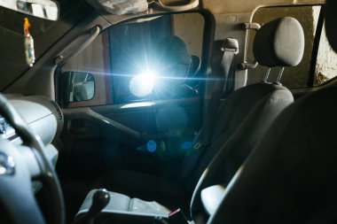 Hırsız karanlık bir yerde el feneri ve tornavidayla bir araç çalıyor.