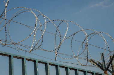 Dikenli tel mavi boyalı metal duvar boyunca uzanan