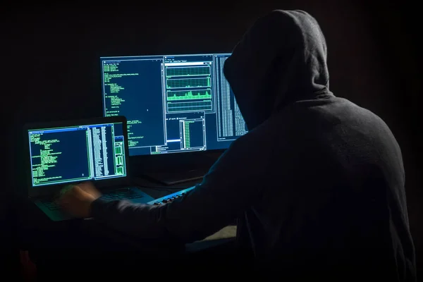 hacker in front of two monitors with computer code