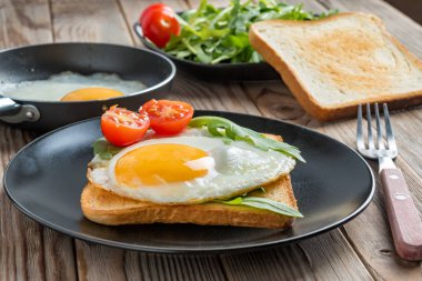 Siyah plaka ve çatal, mantar ve rukkola ile tavada kızarmış yumurta görünümü kadar clouse. Yumuşak odaklama