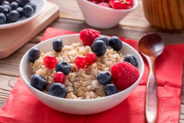 Ahşap arka plan üzerinde yaban mersini ve ahududu ve tahıl ekmek ile lapa yakın görünümü. Sağlıklı kahvaltı.