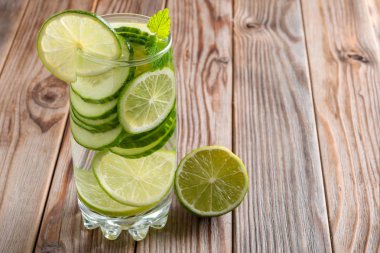 Kireç, salatalık ve nane ile detoks suyu cam karşı ışık ile aydınlatılmış ahşap arka plan. Yumuşak odaklama.