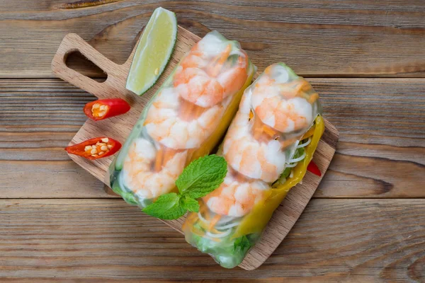 Top view of Vietnamese spring rolls with shrimps on wooden background