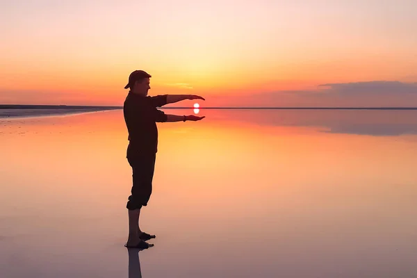 Sole al tramonto tra le mani degli uomini con un riflesso sull'acqua liscia . — Foto Stock