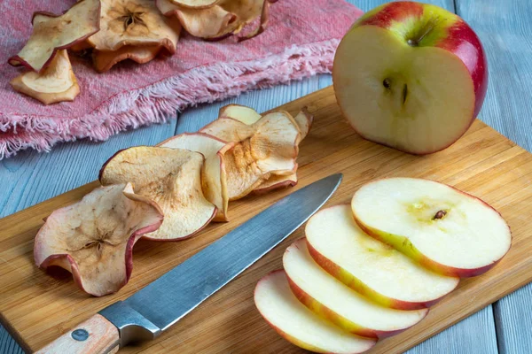 Vista de cerca de sabrosas papas fritas de manzana y manzana roja fresca y cuchillo sobre fondo de madera — Foto de Stock