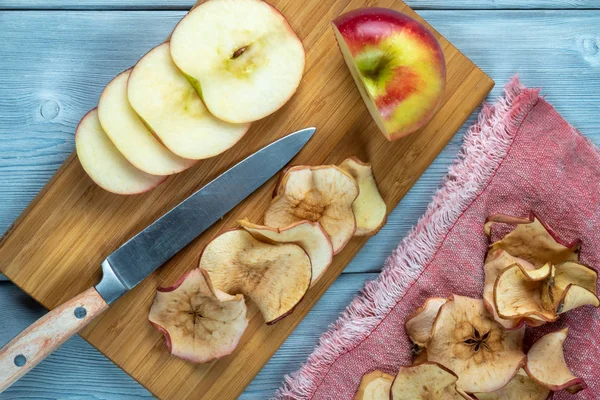 Vista superior de chips de manzana y manzana recién cortada con el cuchillo sobre un fondo de madera — Foto de Stock