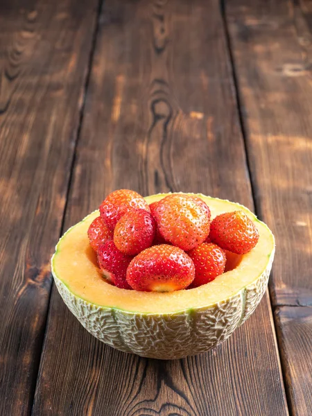 Z bliska widok truskawki w melon na drewnianym tle — Zdjęcie stockowe