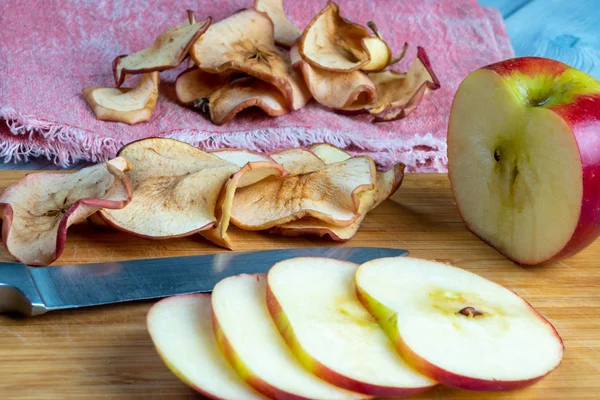 Vista de cerca de las papas fritas de manzana y manzana recién cortada con el cuchillo sobre un fondo de madera. Enfoque suave . — Foto de Stock