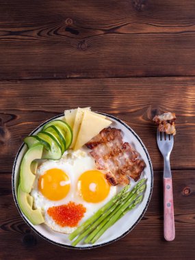 Kopya alanı ile koyu ahşap arka plan üzerinde bir çatal ile beyaz plaka üzerinde ketojenik diyet kahvaltı üst dikey görünümü