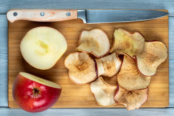 Vista superior de chips de manzana y manzana recién cortada con el cuchillo sobre un fondo de madera — Foto de Stock