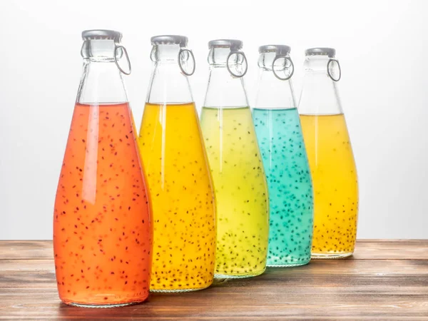Cinco botellas de semilla de albahaca en línea sobre un fondo blanco. Rojo, amarillo, azul claro y verde. Enfoque selectivo —  Fotos de Stock