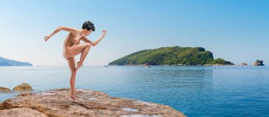 Güzel çıplak kadın pratik yoga bir taş üzerinde açık havada deniz gündüz sırasında teşkil etmektedir