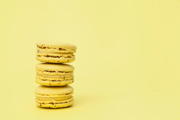 Three yellow macaroon cookies on yellow pastel background