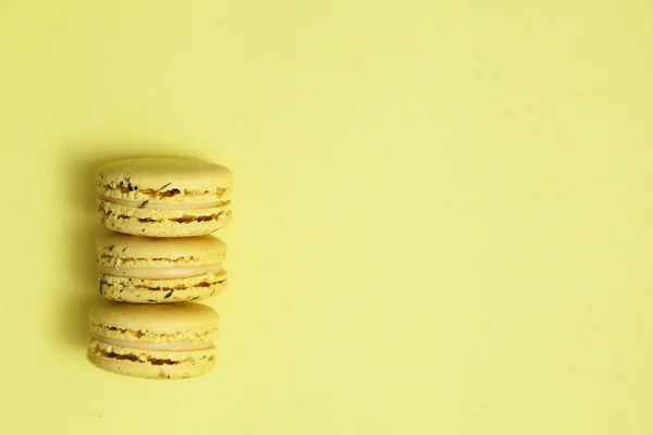 Three yellow macaroon cookies on yellow pastel background