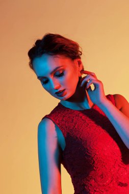 zarif kız boynunu dokunur ve renkli ışıkla tepeden bakıyor