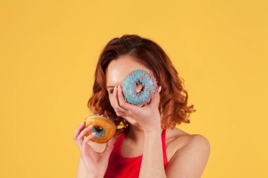 sarı arka planda mavi buzlanma ile kırmızı mayo tutarak Donuts kız