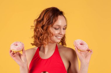 sarı arka planda pembe buzlanma ile kırmızı mayo tutarak Donuts kız