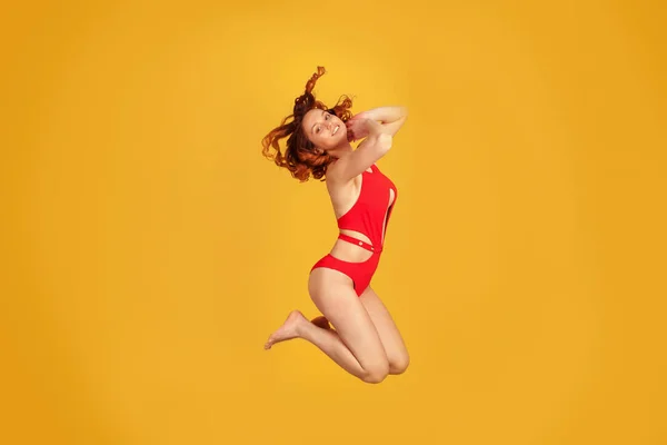 Dziewczyna Czerwonym Strój Kąpielowy Skoki Żółtym Tle — Zdjęcie stockowe