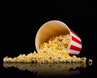 Siyah arka planda izole kağıt çizgili kova dağınık patlamış mısır