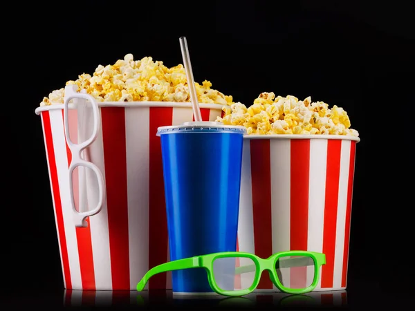 Papiergestreifter Eimer mit Popcorn, Tasse Erfrischungsgetränk und Gläsern auf schwarzem Hintergrund — Stockfoto