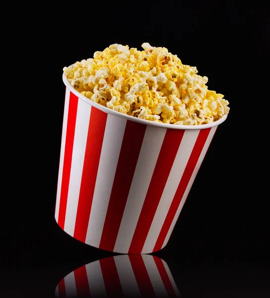 Papier gestreepte emmer met popcorn geïsoleerd op zwarte achtergrond — Stockfoto