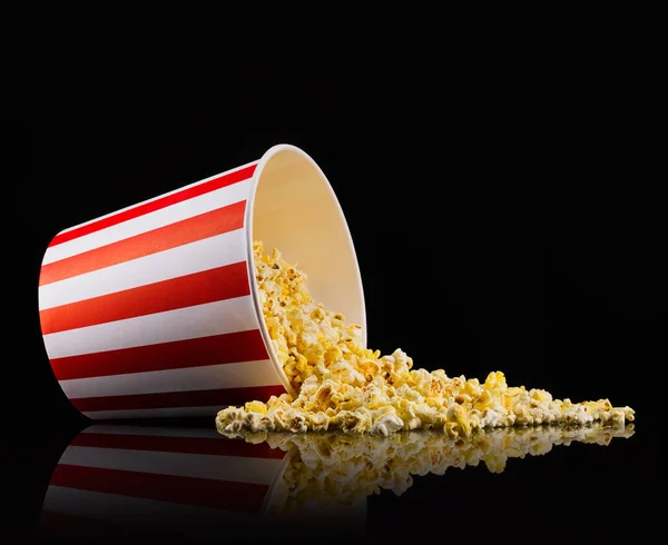 Verstreutes Popcorn aus Papiereimer isoliert auf schwarzem Hintergrund — Stockfoto