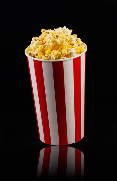Papier gestreepte emmer met popcorn geïsoleerd op zwarte achtergrond — Stockfoto