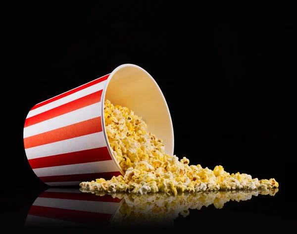 Verstreutes Popcorn aus Papiereimer isoliert auf schwarzem Hintergrund — Stockfoto