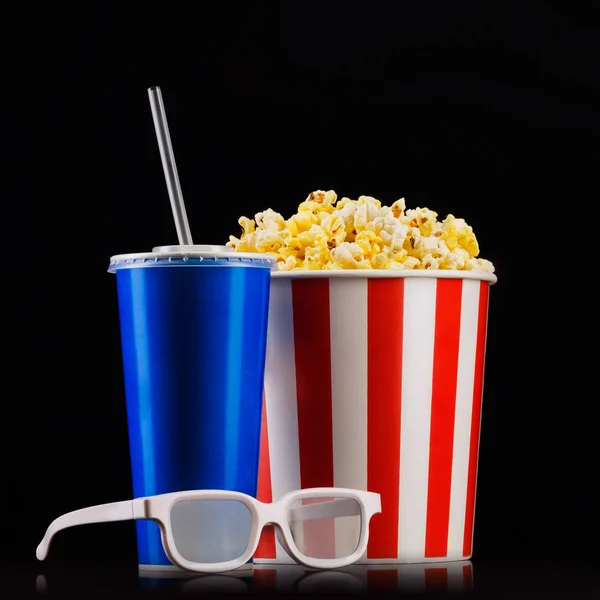 Paper striped bucket with popcorn, cup of soft drink and glasses isolated on black background — Stock Photo, Image