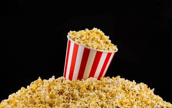 Secchio a strisce di carta installato su popcorn sparsi isolati su sfondo nero — Foto Stock