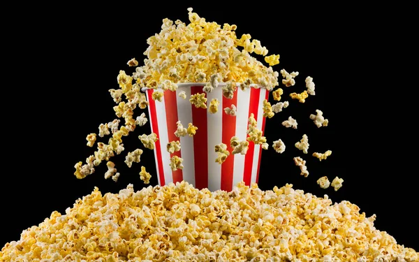 Létající popcorn z proužkované nádoby izolované na černém pozadí — Stock fotografie