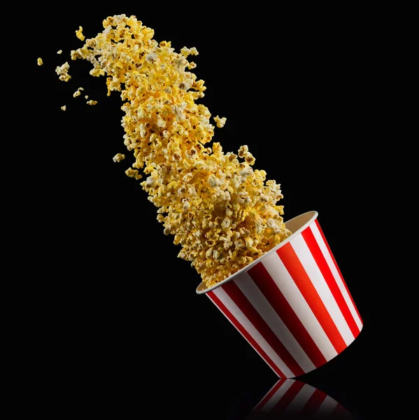 Létající popcorn z proužkované nádoby izolované na černém pozadí — Stock fotografie