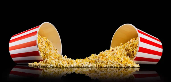 stock image Scattered popcorn from paper striped buckets isolated on black background