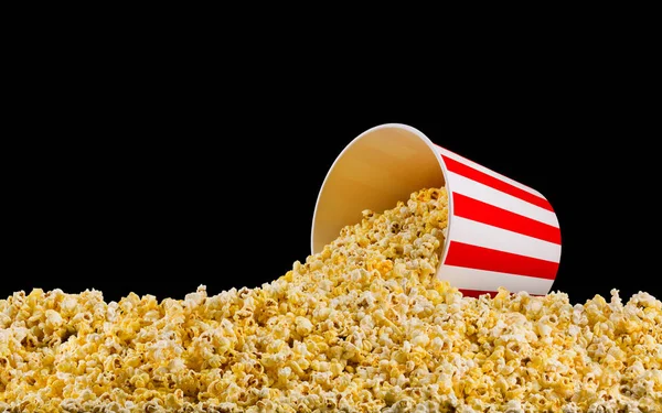 Verspreide popcorn van papier gestreepte emmer geïsoleerd op zwarte achtergrond — Stockfoto