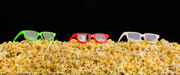 Cinema glasses installed on scattered popcorn isolated on black background — Stock Photo, Image