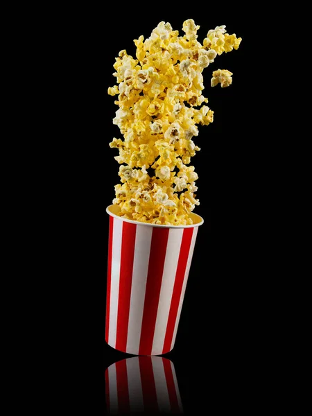 Papier gestreepte emmer met popcorn geïsoleerd op zwarte achtergrond — Stockfoto